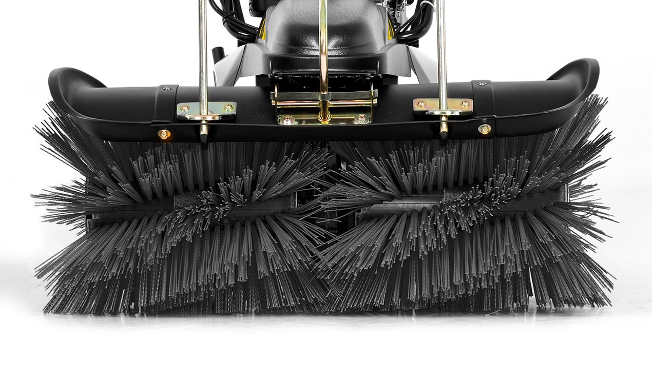 Close-up view of the bristle brushes on an industrial floor sweeper, showing two large, cylindrical rotating brushes with thick black bristles attached to a metal frame.
