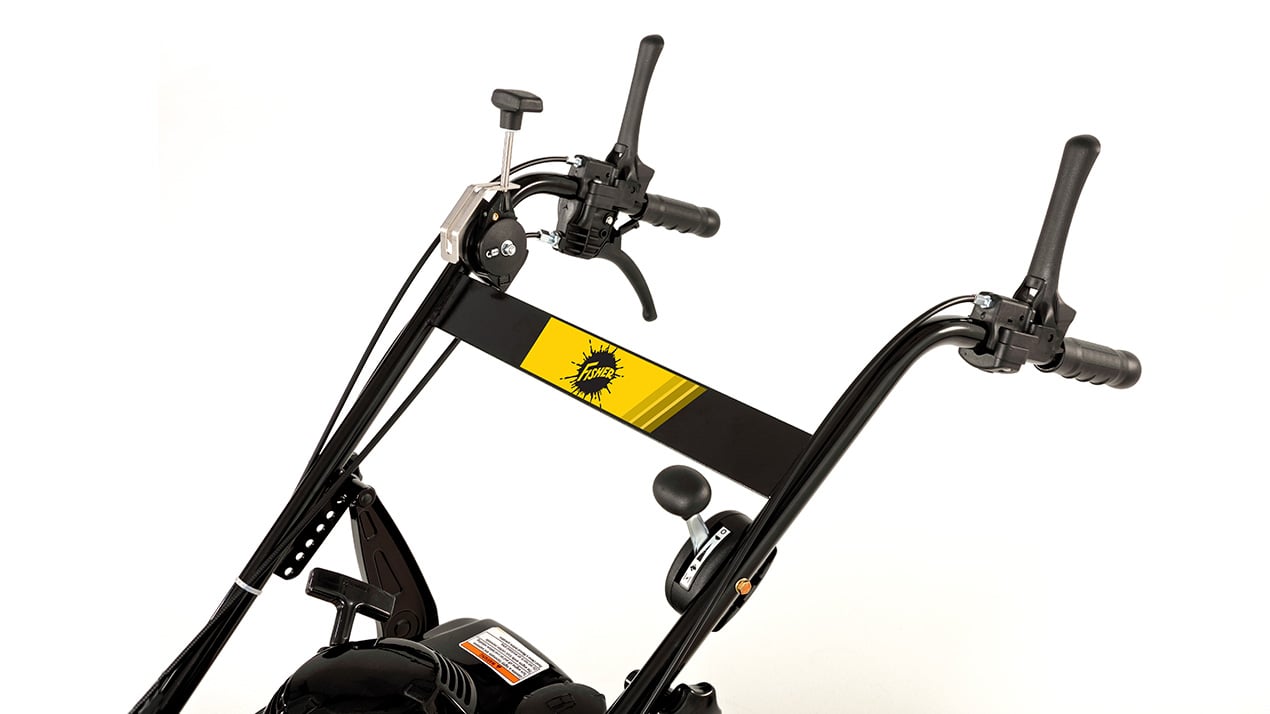 Close-up of the handlebars and control panel of a black and yellow tiller against a white background. The handlebar features levers, a knob, and a yellow stripe with a black logo in the center.