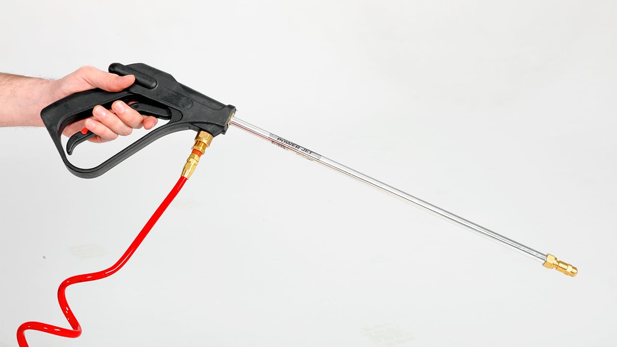 A hand holds a pressure washer spray gun with a long metal wand and a red hose attached, set against a plain white background.