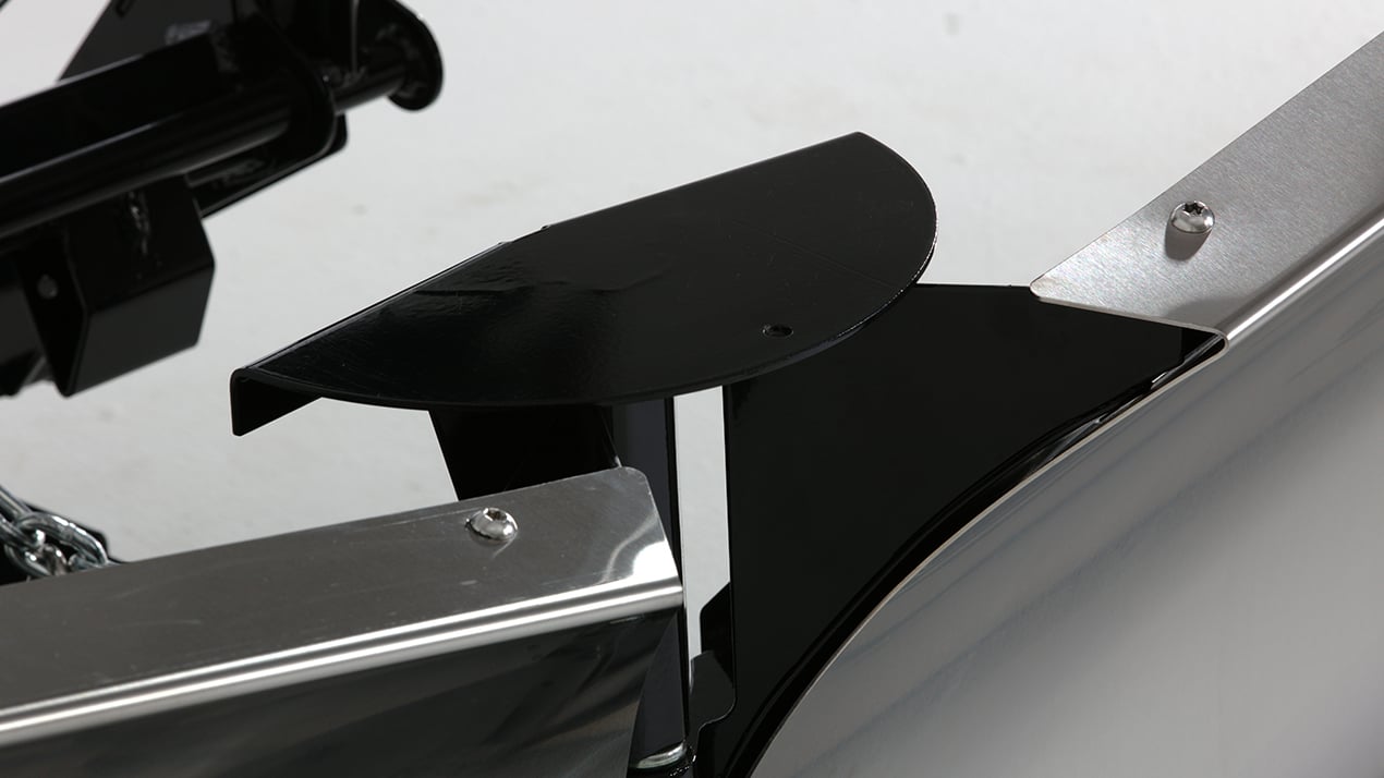 Close-up of a metallic mechanism featuring a black, semi-circular cover and silver components secured with bolts, attached to a larger structure, possibly part of industrial or agricultural equipment.