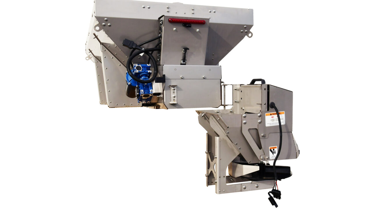 Industrial machine component with a metal frame, switches, blue motor, cables, and caution labels, designed for processing or sorting materials. The unit has several chutes and mechanical parts visible.